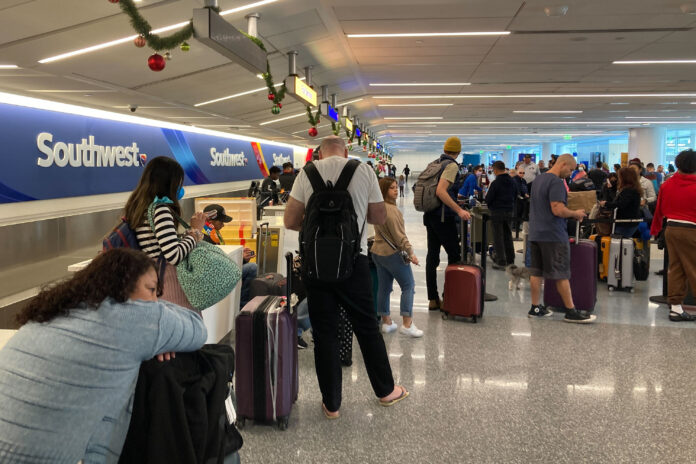TRAVELERS WAIT in long lines at Los Angeles International Airport's Southwest Airlines ticket counter on Monday. The low-cost carrier had to cancel thousands of flights in recent days, including 18 flights at Rhode Island T.F. Green International Airport in Warwick on Tuesday and another nine flights scheduled for Wednesday. / AP PHOTO/EUGENE GARCIA