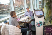 ROLLING OUT: Jacky’s Waterplace Sushi Bar robot server “Bella” waits on a table with Ignacio Davila, left, and Galen Tate. PBN PHOTO/­MICHAEL SALERNO