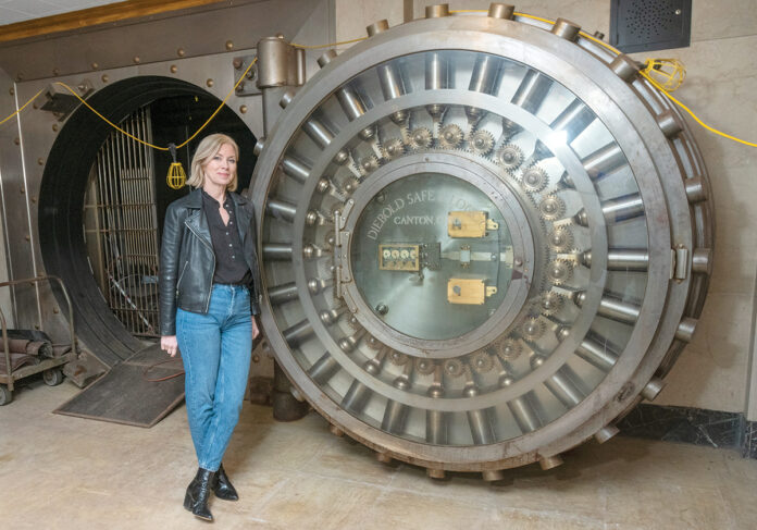 CONVERSATION STARTER:  Compass Real Estate agent Kira Greene stands outside the vault that comes with a former Pawtucket bank she is marketing as a candidate for residential conversion.  PBN FILE PHOTO/­MICHAEL SALERNO