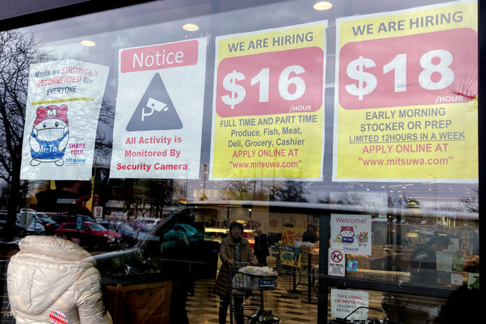 IN THE OPEN: Hiring signs displayed at a grocery store in Arlington Heights, Ill., tout the pay rate. Employers are increasingly posting salary ranges for job openings, even in states where it’s not mandated by law.  AP FILE PHOTO/NAM Y. HUH