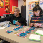 SAFETY FIRST: Dennis Bailer, left, overdose prevention program director at Project Weber/RENEW, and Izzie Irizarry, lead case manager, assemble safe injection kits at the agency’s South Providence drop-in center. Project Weber/RENEW and CODAC Inc. are scheduled to open a harm reduction site in early 2024. PBN PHOTO/­MICHAEL SALERNO