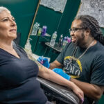 REPEAT CUSTOMER: Joseph Becton, owner of F.I.N.A.O. Tattoo Ink in North Providence, designs an extension for Donna Ruggieri of West Warwick, who said Becton took very good care of her previous tattoo.   PBN PHOTO/MICHAEL SALERNO