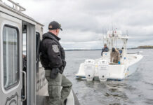 HELP WANTED: There are 1,700 unfilled state jobs, but has anyone noticed? NAVIGATING SHORTAGES:
R.I. environmental police officer Jacob Malone, left, checks the size of striped bass caught by two unidentified fishermen in Narragansett Bay. The R.I. Department of Environmental Management says staff shortages have made it difficult to schedule such law enforcement operations.
PBN PHOTO/
DAVID HANSEN