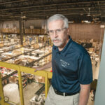 MULTISTEP PROCESS: ChemArt President David Marquis, standing above the Lincoln manufacturer’s factory floor, says the process to create the company’s popular Christmas ornaments, which number more than 1 million orders annually, involves designing, etching, digital, as well as screen printing and plating aspects.