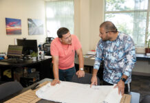 PLANNING AHEAD: James Hernandez, left, E2SOL LLC’s lead electrician, and Brandon Baro, field site support specialist, look over design plans at the renewable energy firm’s Providence office.  PBN PHOTO/TRACY JENKINS
