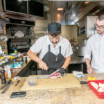 FISH FILET: William Bangs, right, executive sous chef at The Chanler at Cliff Walk in Newport, observes as demi sous chef Nicolas Rizzo ­prepares a black sea bass. PBN PHOTO/MICHAEL SALERNO