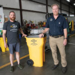 COLLECTING SCRAPS: Leo Pollock, left, and Nat Harris, co-founders of organic waste collector ReMix Organics Co. in Providence, use these yellow bins to gather food waste, which either goes to farms for compost or is turned into energy such as electricity or a renewable gas.  PBN PHOTO/MICHAEL SALERNO