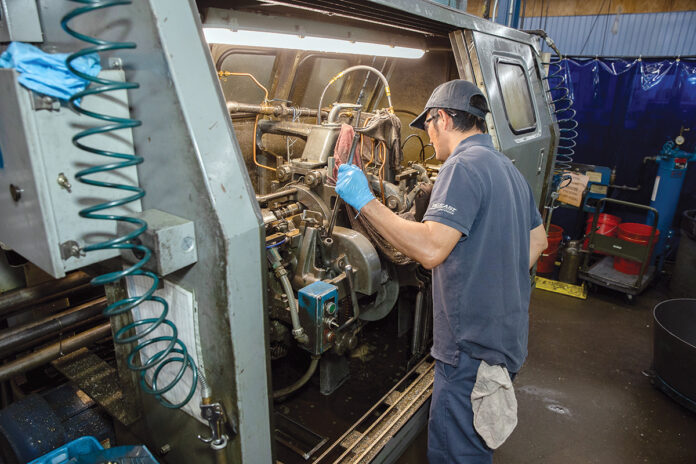 TUNING UP: Lang Yang, a davenport operator at Groov-Pin Corp., evaluates the inner workings of a machine at the Smithfield-based manufacturer.  PBN PHOTO/TRACY JENKINS