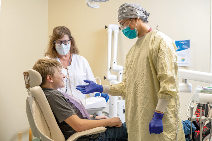 OPEN UP: Dentist Milton J. Liu, right, and dental assistant Lori Beth Adler prepare to examine the teeth of patient Anthony Northup at Wood River Health in Hopkinton.  COURTESY WOOD RIVER HEALTH