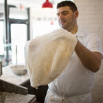 SPREAD THIN: Robert Andreozzi, co-owner and chef of Pizza Marvin, prepares dough for a pizza at the restaurant on Wickenden Street in Providence. In December 2022, a rave review on social media from Barstool Sports owner Dave Portnoy spurred so many orders, it disrupted the business for a time. PBN PHOTO/RUPERT WHITELEY