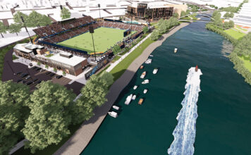 VENUE VIEW: A rendering of what the Tide­water Stadium in Pawtucket is supposed to look like when completed in 2025. At the top of the image is a mixed-use building that has been proposed for Phase 1B, as well as a pedestrian bridge across the Seekonk River to structures that would be part of Phase 2. COURTESY FORTUITOUS PARTNERS LLC