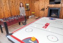 ALL ABOUT FUN: Allie Readyhough Shore, broker associate at Mott & Chace Sotheby’s International Realty, stands in a fully stocked game room in the basement of a home in South Kingstown. These types of amenities and much more are a big trend in high-end homes these days.  PBN PHOTO/­MICHAEL SALERNO