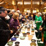 ATTENDEES OBSERVE a collection of bowls during the Rhode Island Community Food Bank's Empty Bowls fundraiser in 2019. The Empty Bowls fundraiser returns March 27 at the WaterFire Arts Center in Providence. / COURTESY RHODE ISLAND COMMUNITY FOOD BANK