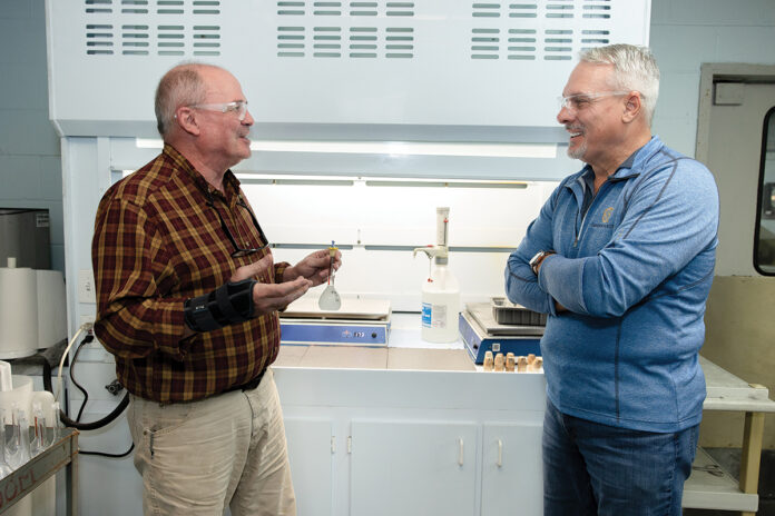 GETTING A BRIEFING: Dana Evans, left, lab director at Gannon & Scott Inc. in Cranston, discusses business with Chris Jones, the company president. Gannon & Scott is one of the Rhode Island firms that have been honored by the federal government for its hiring of military veterans. Jones also served in the R.I. Army National Guard. PBN PHOTO/TRACY JENKINS