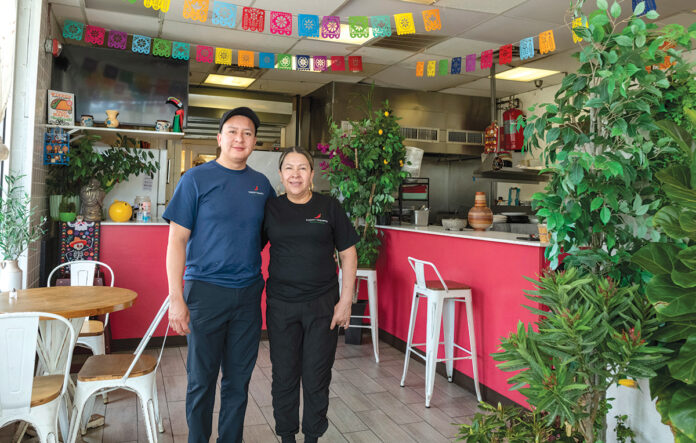 PART OF THE FAMILY: Eddi Alcantar, left, with his mother, Maria Alcantar, in Tuxpan Taqueria in Central Falls. They are just some of the members of the Alcantar family who run the Broad Street eatery.  PBN PHOTO/MICHAEL SALERNO