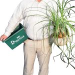 the prop Matthew A. Fannon poses with a plant from his office and a recycling bin, representing the different recycling streams that have been established on the Johnson & Wales University campus.