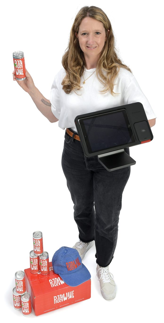 the prop  Elizabeth McDonnell holds a Lightspeed point-of-sale hardware system, representing her occupation, and a case of Pizza Wine, which is  her side business she launched last month.