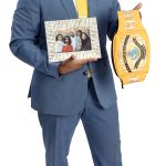 the prop  Mario Zuluaga holds a photo of his family and a WWE championship belt, symbolizing “the spirit of a champion” and overcoming challenges.