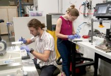 LAB WORK: Michael Molinski, head of research and development at Audience Inc., is shown assembling cells inside the company’s lab at the Ocean Technology Center on the Bay Campus at the University of Rhode Island in Narragansett. Also pictured is Hailey Simon, head of operations for the company.  PBN PHOTO/PAUL J. SPETRINI