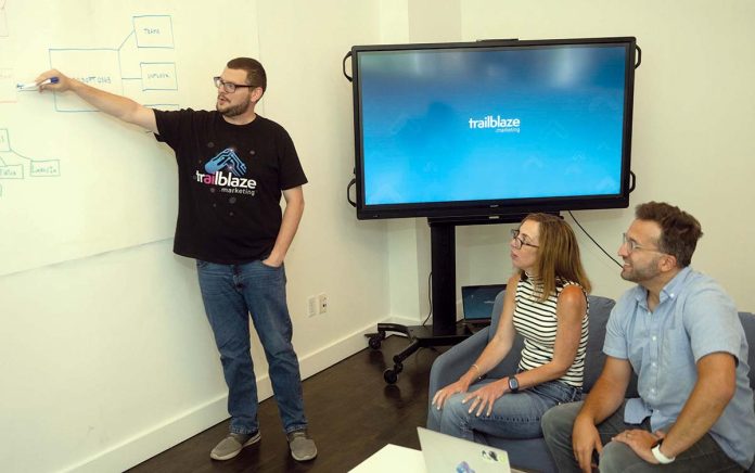 PLANNING AHEAD: Trailblaze Marketing Digital Media Manager Kyle Steinberg, left, shares ideas with co-worker Jen Guimond, center, and company founder and President Christopher Parisi.
PBN PHOTO/PAUL J. SPETRINI PLANNING AHEAD: Trailblaze Marketing Digital Media Manager Kyle Steinberg, left, shares ideas with co-worker Jen Guimond, center, and company founder and President Christopher Parisi.
PBN PHOTO/PAUL J. SPETRINI