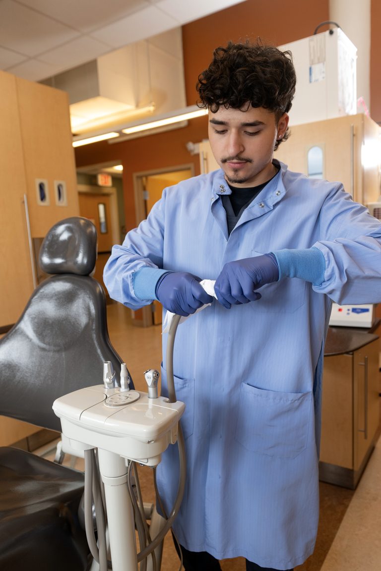 WIPE DOWN: Anderson Mendoza wipes down a patient area and dental instruments at The Providence Community Health Centers Inc.
PBN PHOTO/PAUL J. SPETRINI