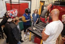 HANDS ON:  Teacher candidate Jessica Barresi, center, holds a metal box she worked on in a welding program that is part of a teacher certification program at Roger Williams University run by Lynne Bedard, center right. Also pictured, from left, foreground: Coventry High students Brayden Assadorian (wearing ­welding helmet) and James Spencer, and teacher candidates Jennifer Ortiz, back left; Anthony Carrion, foreground center right; and Louis Petrucci, right. PBN PHOTO/TRACY JENKINS