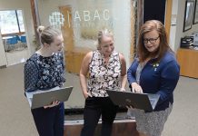 FINDING SOLUTIONS: Patricia Joyce, right, senior account manager, and account managers Sarah Murphy, left, and Alysha Beaudry work on their laptops at the Cranston office of e-health technology company Abacus Health Solutions LLC.  PBN PHOTO/ELIZABETH GRAHAM