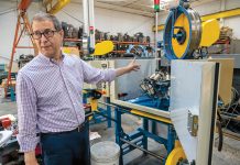 Woven into worldwide success TOTAL PACKAGE: Wardwell Braiding Co. Vice President John Tomaz points to one of the company’s braiding machines on its factory floor in Central Falls. Wardwell not only designs, builds and sells the machines; it also produces and provides replacement parts and performs repairs.
PBN PHOTO/MICHAEL SALERNO