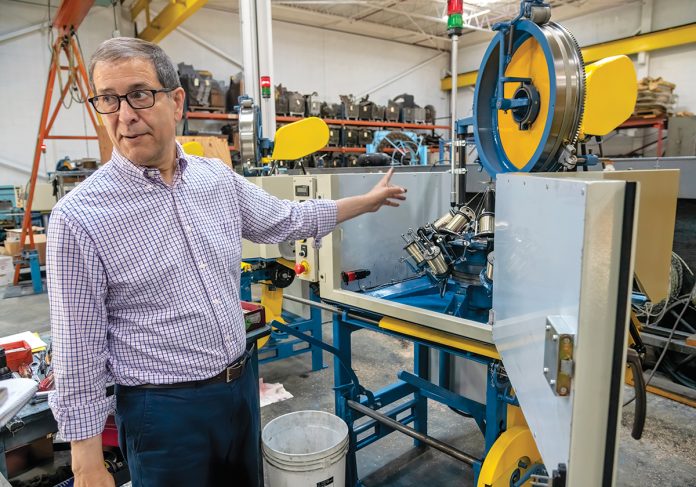 TOTAL PACKAGE: Wardwell Braiding Co. Vice President John Tomaz points to one of the company’s braiding machines on its factory floor in Central Falls. Wardwell not only designs, builds and sells the machines; it also produces and provides replacement parts and performs repairs. PBN PHOTO/MICHAEL SALERNO