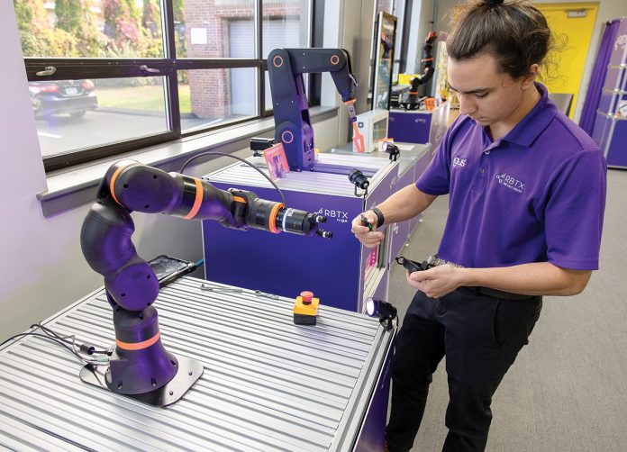 STRONG ARM: Igus Bearings Inc. intern Jaden Stone programs a robotics arm that the East Providence-based company produces.  PBN PHOTO / TRACY JENKINS