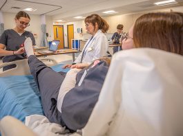 PRACTICE TIME: Johnson & Wales University nursing student Cassidy Titchenell conducts an exam on fellow student Caitlin Murdock at the university’s nursing facilities in Providence. The students are part of JWU’s accelerated nursing degree program. Looking on is nursing student Elena Wertenbaker.  COURTESY ­JOHNSON & WALES UNIVERSITY