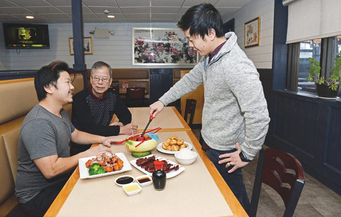 ALL IN THE FAMILY: Brothers John Lau, left, and James Lau,  right, are the managers  of the Chinese restaurant New Dragon Inc. in  Narragansett, which they co-own with their father, Chung Hing Lau, center, who founded the restaurant 30 years ago and is now semi-retired from the business. PBN PHOTO/ELIZABETH GRAHAM