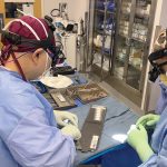 PRE-OP PREP: Dr. Clark Chen, left, director of the brain tumor program at Rhode Island Hospital, and Dr. Joshua Feler, a medical resident, prepare the GammaTile implants – the small white squares – for a recent ­procedure.  ­COURTESY BROWN ­UNIVERSITY HEALTH