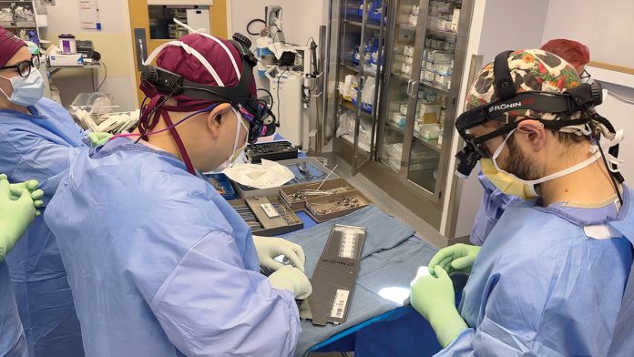 PRE-OP PREP: Dr. Clark Chen, left, director of the brain tumor program at Rhode Island Hospital, and Dr. Joshua Feler, a medical resident, prepare the GammaTile implants – the small white squares – for a recent ­procedure.  ­COURTESY BROWN ­UNIVERSITY HEALTH