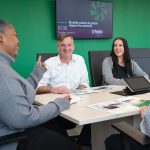 TALKING IT OUT: Sean Daly, center, People’s Credit Union CEO and president, meets with members of his staff at the credit union’s headquarters in Middletown. With Daly is Denise Cole, left, and Cassandra Camara. People’s is among the Rhode Island credit unions that have seen a drop in yearly net income in 2023 and 2024 because of the interest rate environment.  PBN PHOTO/DAVID HANSEN