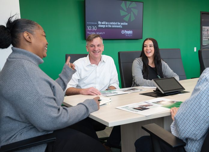 TALKING IT OUT: Sean Daly, center, People’s Credit Union CEO and president, meets with members of his staff at the credit union’s headquarters in Middletown. With Daly is Denise Cole, left, and Cassandra Camara. People’s is among the Rhode Island credit unions that have seen a drop in yearly net income in 2023 and 2024 because of the interest rate environment.  PBN PHOTO/DAVID HANSEN