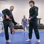 ON THE MAT:  Nic Cortes, left, owner of the jiu-jitsu studio Cortes BJJ LLC in Warwick, teaches Kevin Madden of Warwick a mixed martial arts move. Cortes, a minority business owner, recently opened a second location in the city.  PBN PHOTO/ MICHAEL SALERNO