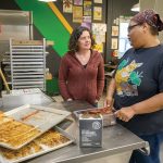 STAYING AFLOAT: Delite Primus, left, director of advancement for Farm Fresh Rhode Island, speaks with Harvest Kitchen Production Manager Charreese Braxton at Farm Fresh’s Providence location on Sims Avenue. Farm Fresh recently had to lay off four employees and is seeking financial assistance amid a federal funding freeze imposed by President Donald Trump’s administration. PBN PHOTO/MICHAEL SALERNO