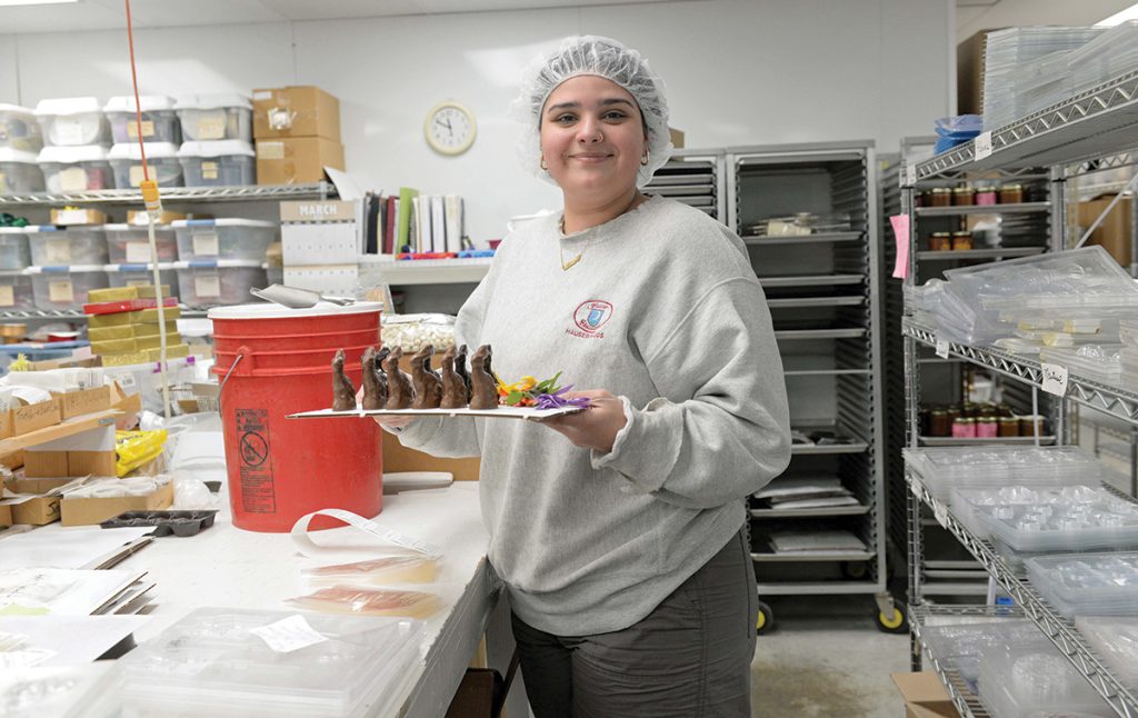 SWEET TREATS: Aasha Hauser, a student and third-generation employee at Hauser Chocolatier, with some of the company’s products on the manufacturing floor in Westerly.
PBN PHOTO/ELIZABETH GRAHAM