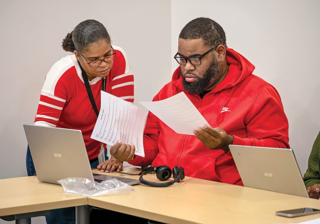Betty Tavares, library lead technology teacher, assists David Crawley, of Providence, during a Microsoft Excel class for adult English language learners.
PBN PHOTO/MICHAEL SALERNO