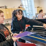 MAKER SPACE: ­Instructor Adaliz Rivera, above right, teaches Jasper Bliss, of Providence, how to operate a heat press and vinyl cutting machine in the first-floor workshop at Providence Public Library.  PBN PHOTO/­MICHAEL SALERNO