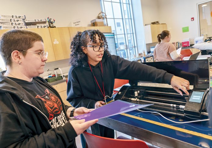 MAKER SPACE: ­Instructor Adaliz Rivera, above right, teaches Jasper Bliss, of Providence, how to operate a heat press and vinyl cutting machine in the first-floor workshop at Providence Public Library.  PBN PHOTO/­MICHAEL SALERNO