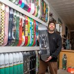 ROLLING ALONG: Cheyne Cousens moved back from California in 2023 to run his father’s Elemental Surf and Skate shop in Middletown, which he rebranded Omen after an idea that began as a hobby in 2014 with printed-up T-shirts with logos and artwork he personally designed.  PBN PHOTO/KATE WHITNEY LUCEY