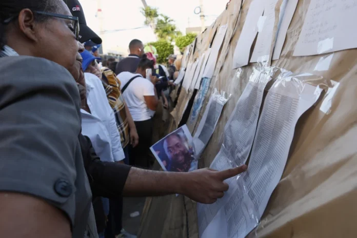 PEOPLE SEARCHING for their missing relatives peruse a list of names outside the Jet Set nightclub after its roof collapsed during a merengue concert in Santo Domingo, Dominican Republic, Tuesday. Fray Luis Rosario, a Federal Hill restaurateur, was among the dead. / ASSOCIATED PRESS FILE PHOTO/RICARDO HERNANDEZ