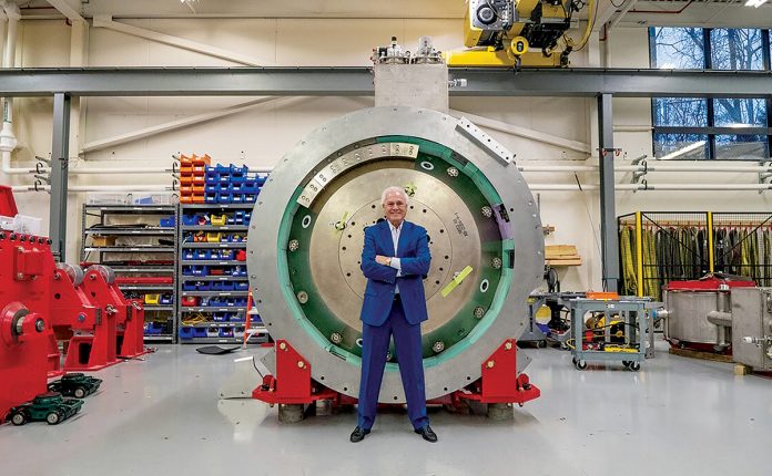 HEAVY METAL: Gregory Mercurio, senior vice president of radiation oncology for American Shared Hospital Services and CEO of Precision Radiation Oncology of Rhode Island, stands in front of a cyclotron, which generates particles that create the protons used in proton beam radiation therapy for cancer patients. The cyclotron must be surrounded by a vault, which together weigh 230,000 pounds. COURTESY GREGORY MERCURIO