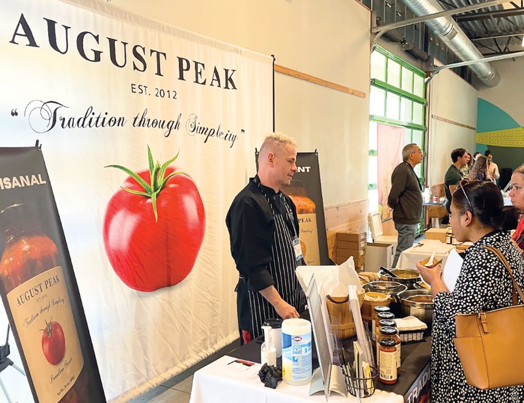 GETTING A TASTE: August Peak Tomato Sauces owner and chef William Ferlauto talks with attendees at the Hope & Main Tabletop Show, a wholesale food show and marketplace, at Farm Fresh Rhode Island in Providence on April 22.
COURTESY HOPE & MAIN