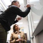 ALL IN: Dawn Apajee, right, owner and founder of professional staffing service City Personnel Inc., says the company is not pulling back on its commitment to diversity, equity and inclusion. Writing on the board above is Recruiting Coordinator Adora Andrade. PBN FILE PHOTO/­MICHAEL SALERNO