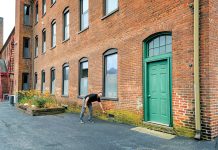 ON THE MARK: Richard Grundy, CEO and president of AVTECH Software Inc., indicates the level of floodwater at Cutler Mill in Warren, where AVTECH’s offices are located.  PBN PHOTO/MICHAEL SALERNO