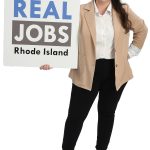 the prop Alyssa Alvarado holds the  Real Jobs Rhode Island sign, symbolizing her decade-plus time working to grow the state’s workforce development program.