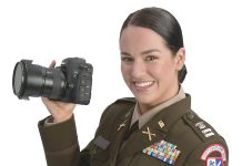 the prop Alexandra Curtis holds a camera and microphone with the R.I. National Guard logo, representing the many capabilities of public affairs soldiers.